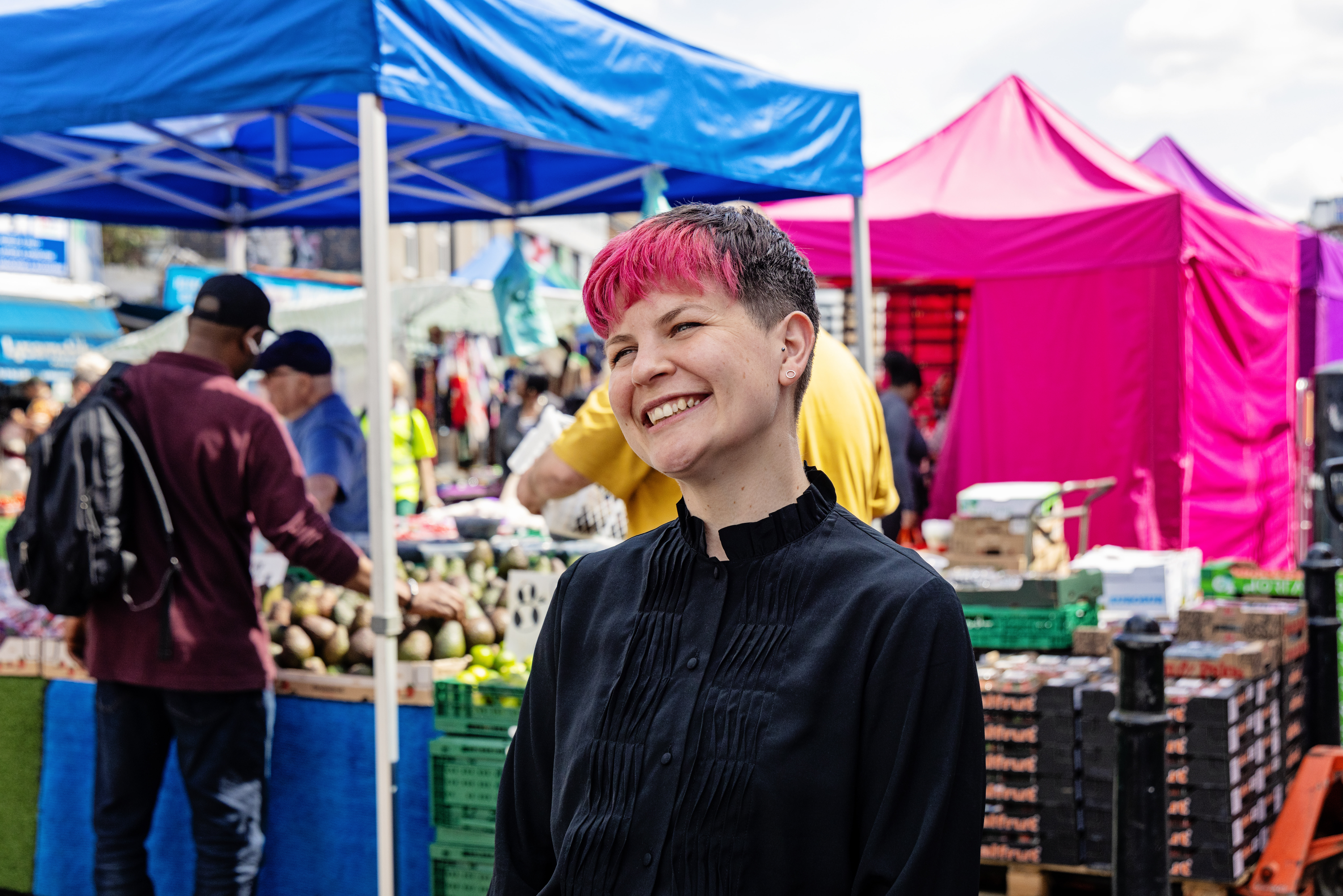 Zoë Garbett AM smiles in front of Ridley Road market