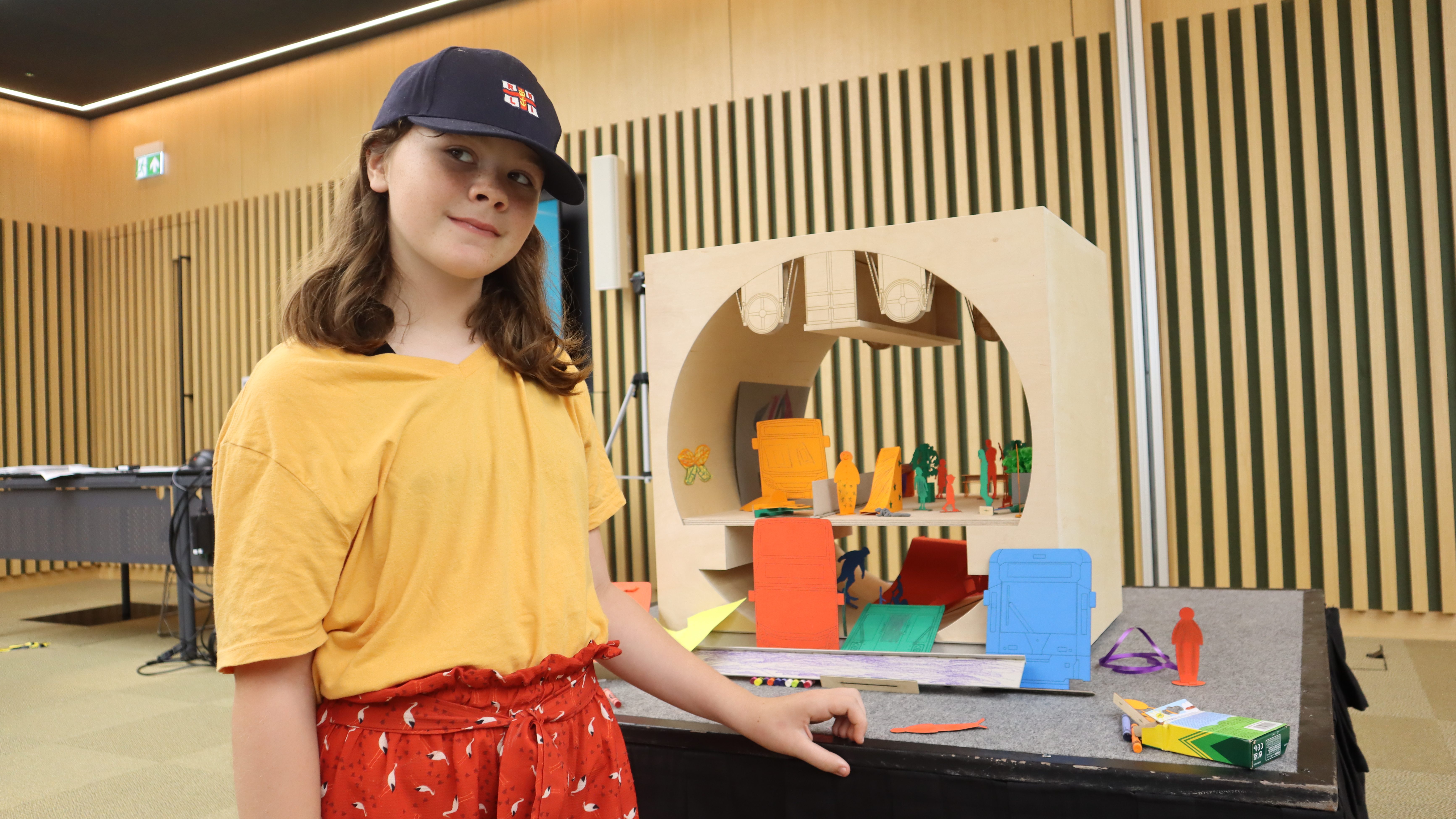 A young Londoner stands in front of Siân Berry's miniature model of the Silvertown Road Tunnel, looking off into the distance.